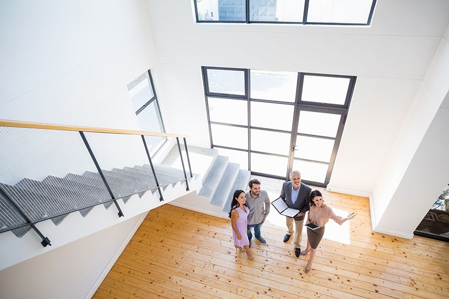 About Our Agency - View of Two Real Estate Agents Showing a Couple Around an Empty Spacious Modern Home